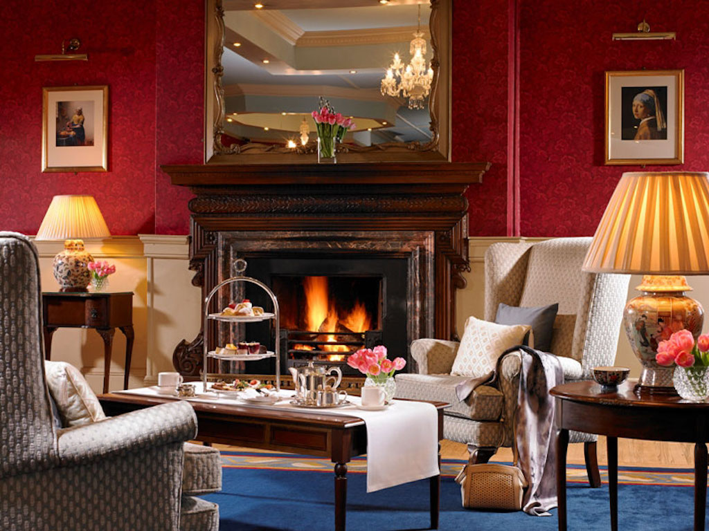 Opulent drawing room with a lit fire, chandeliers and afternoon tea setting at Knockranny House Hotel and Spa, County Mayo.