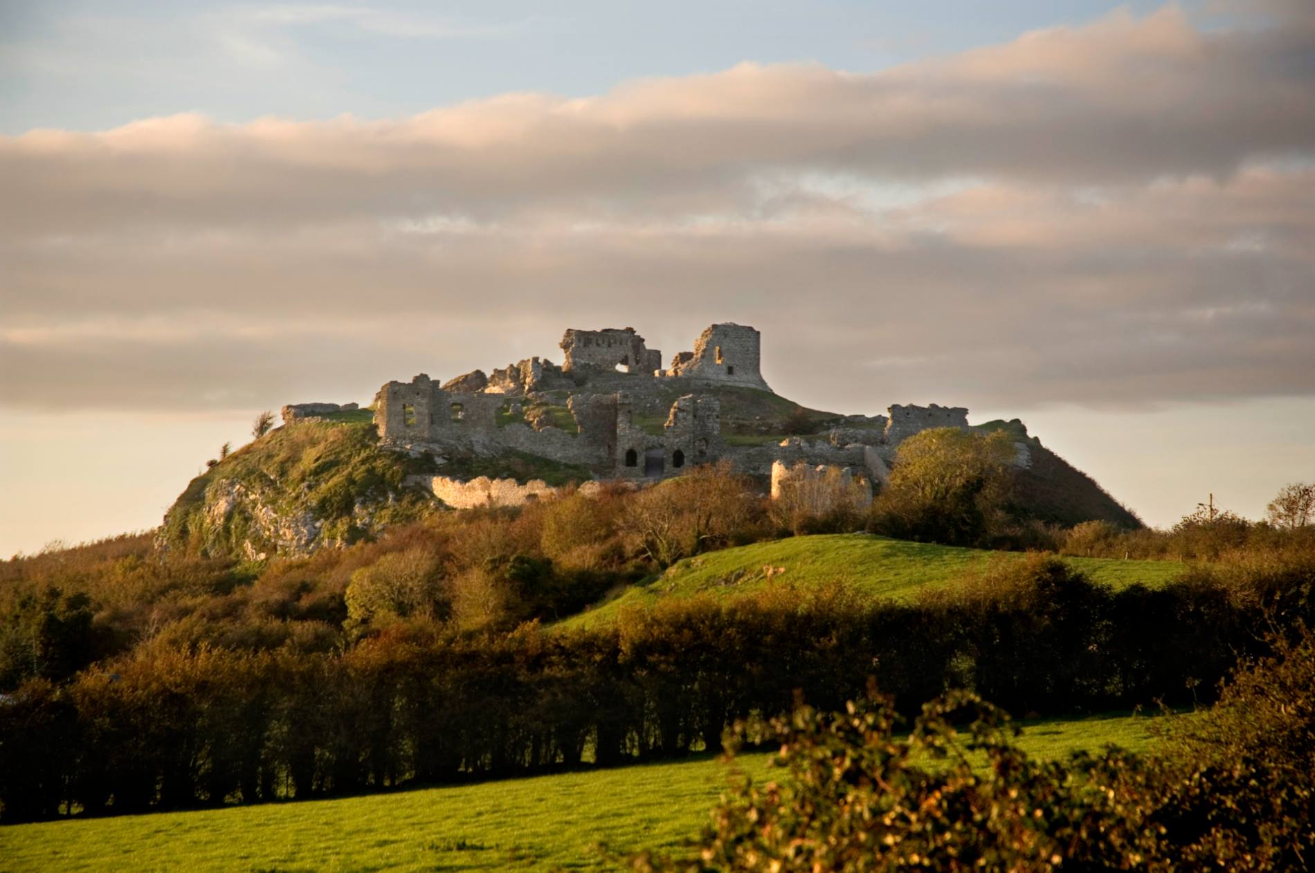 Ruins of a hilltop fortress bathed in golden light at sunset on the Rock of Dunamase in Ireland’s Ancient East.