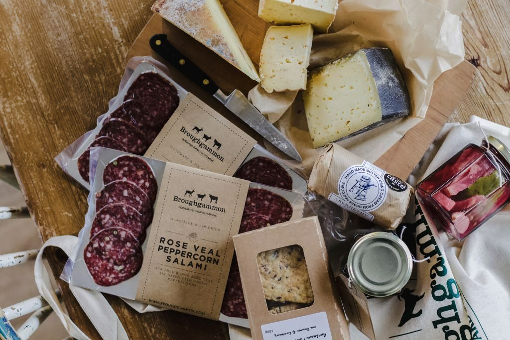 Artisan food selection from Broughgammon, County Antrim, with salami, cheeses, and preserves on a rustic table.