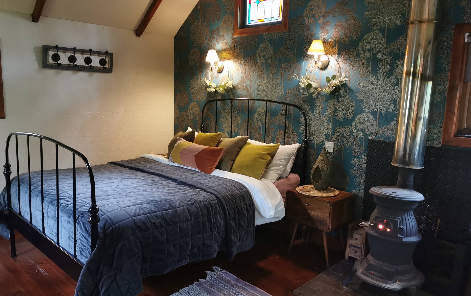 Rustic bedroom with iron bed and wood stove at Teapot Lane Glamping, County Leitrim.