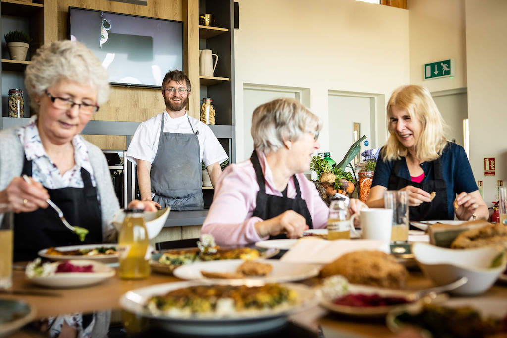 Group taking part in a cookery class at Airfield Estate in Dublin with a smiling chef leading.