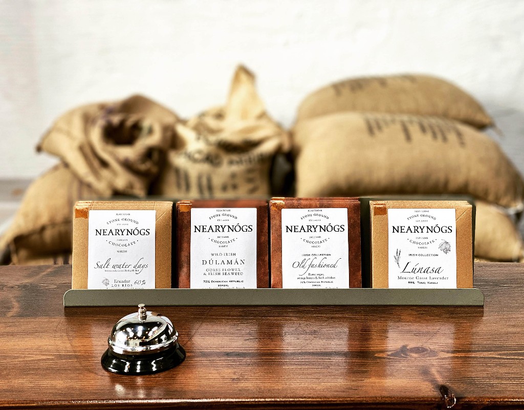 Four NearyNógs chocolate bars on a wooden counter, with hessian coffee sacks in the background.
