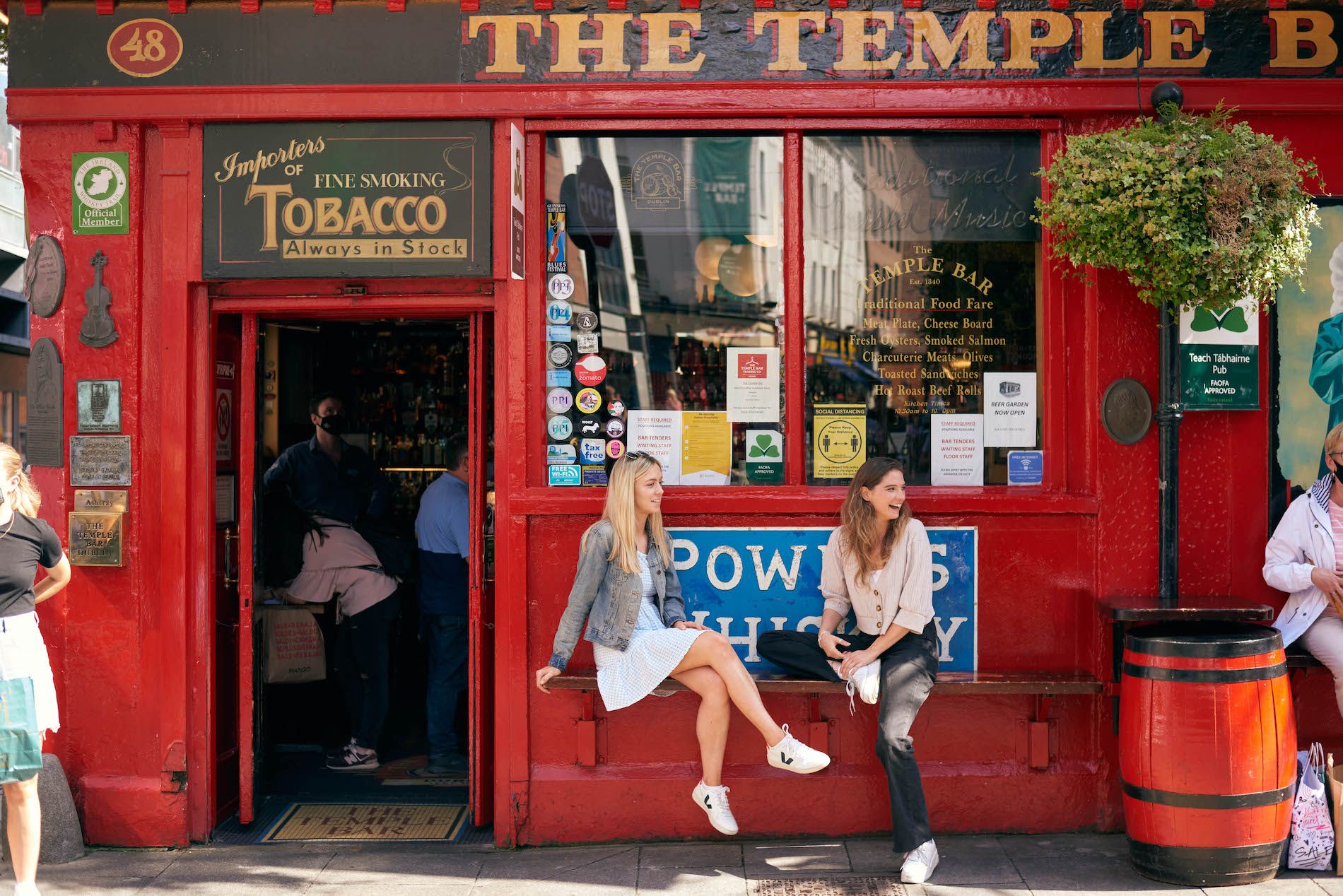 Two women chatting outside the red-painted Temple Bar pub in Dublin’s cultural quarter.