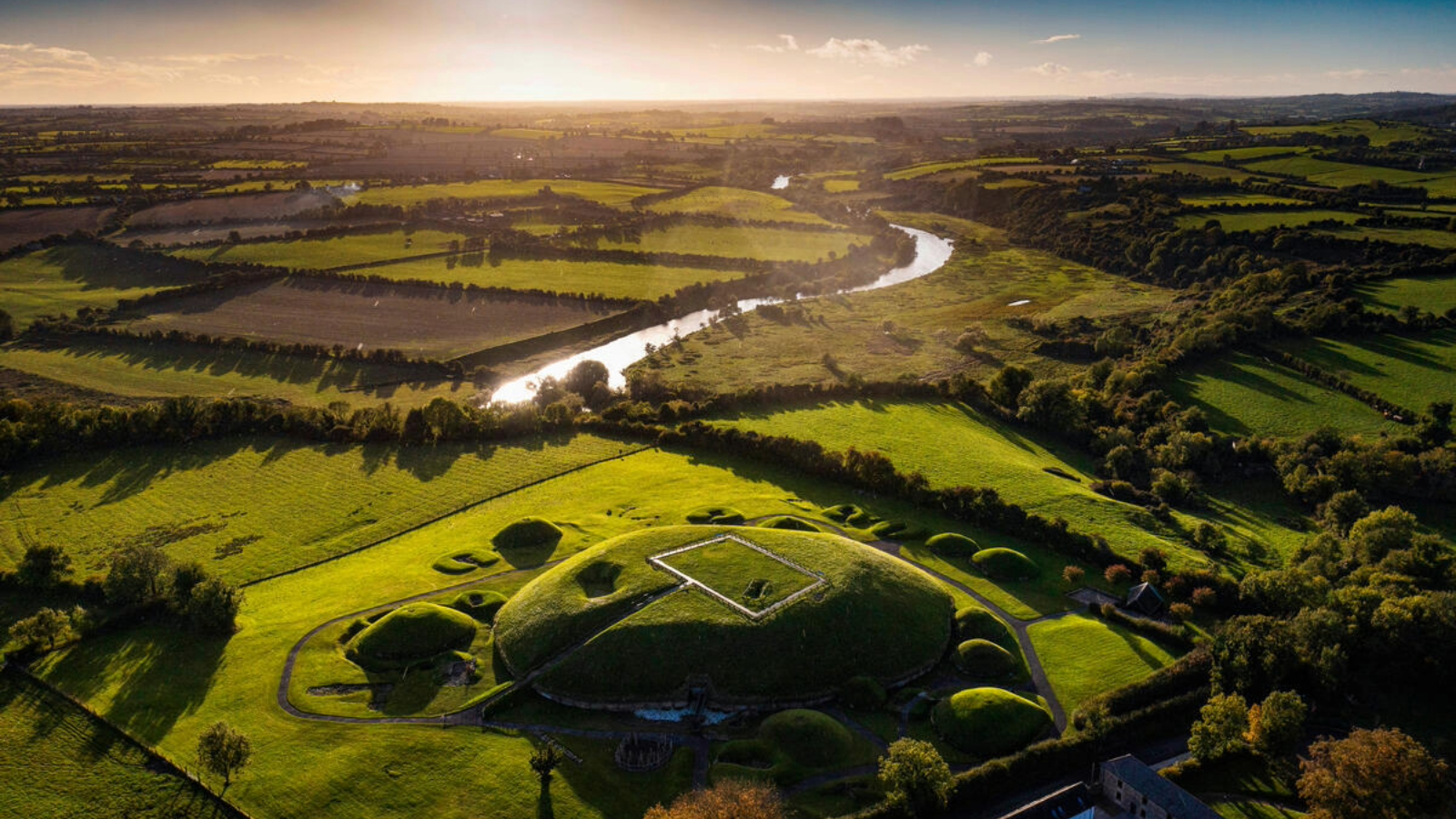 Aerial view of Knowth passage tomb and surrounding farmland beside the River Boyne, County Meath.