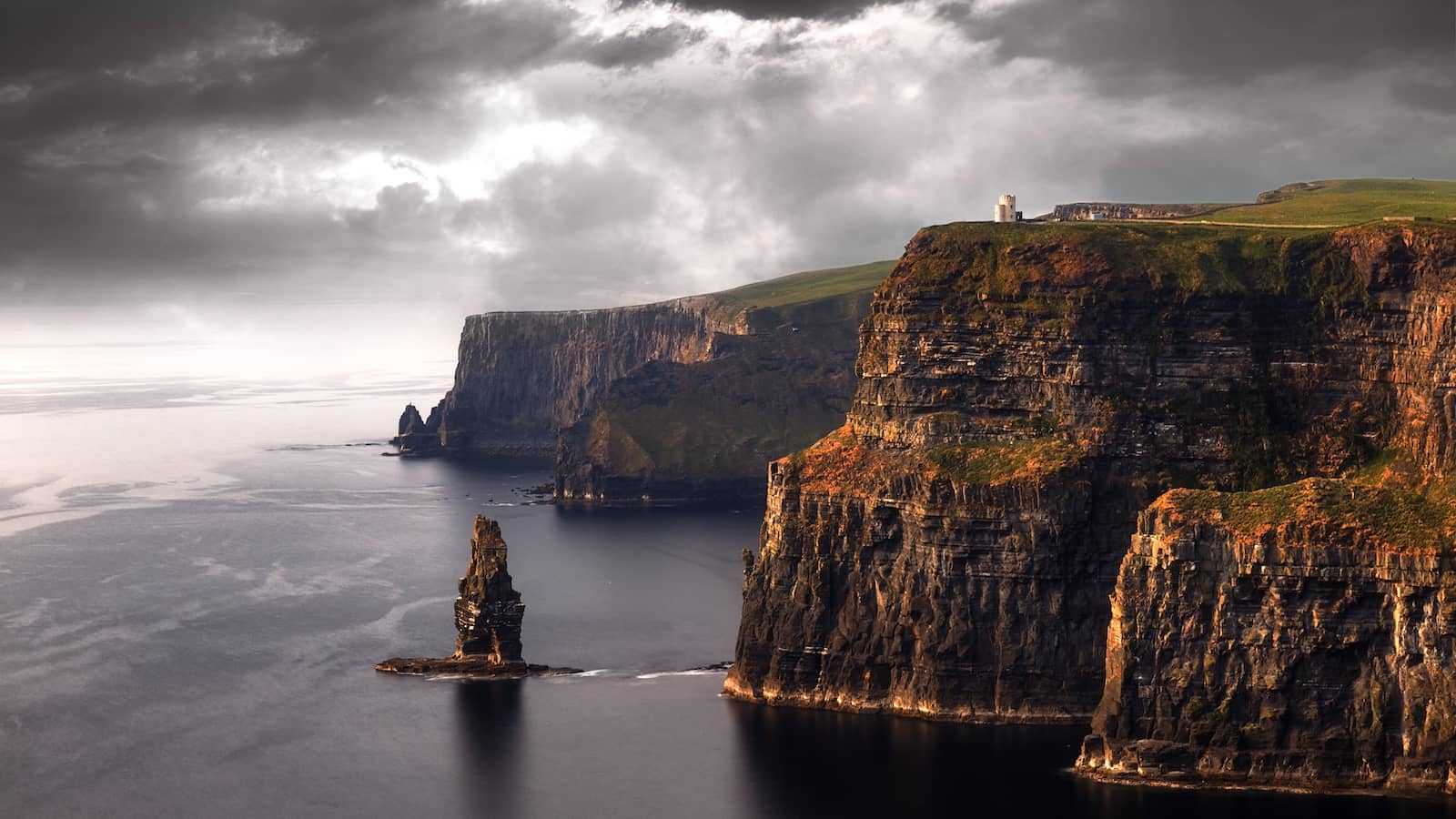 Moody Atlantic light over the Cliffs of Moher with a rugged sea stack and O’Brien’s Tower on the headland.