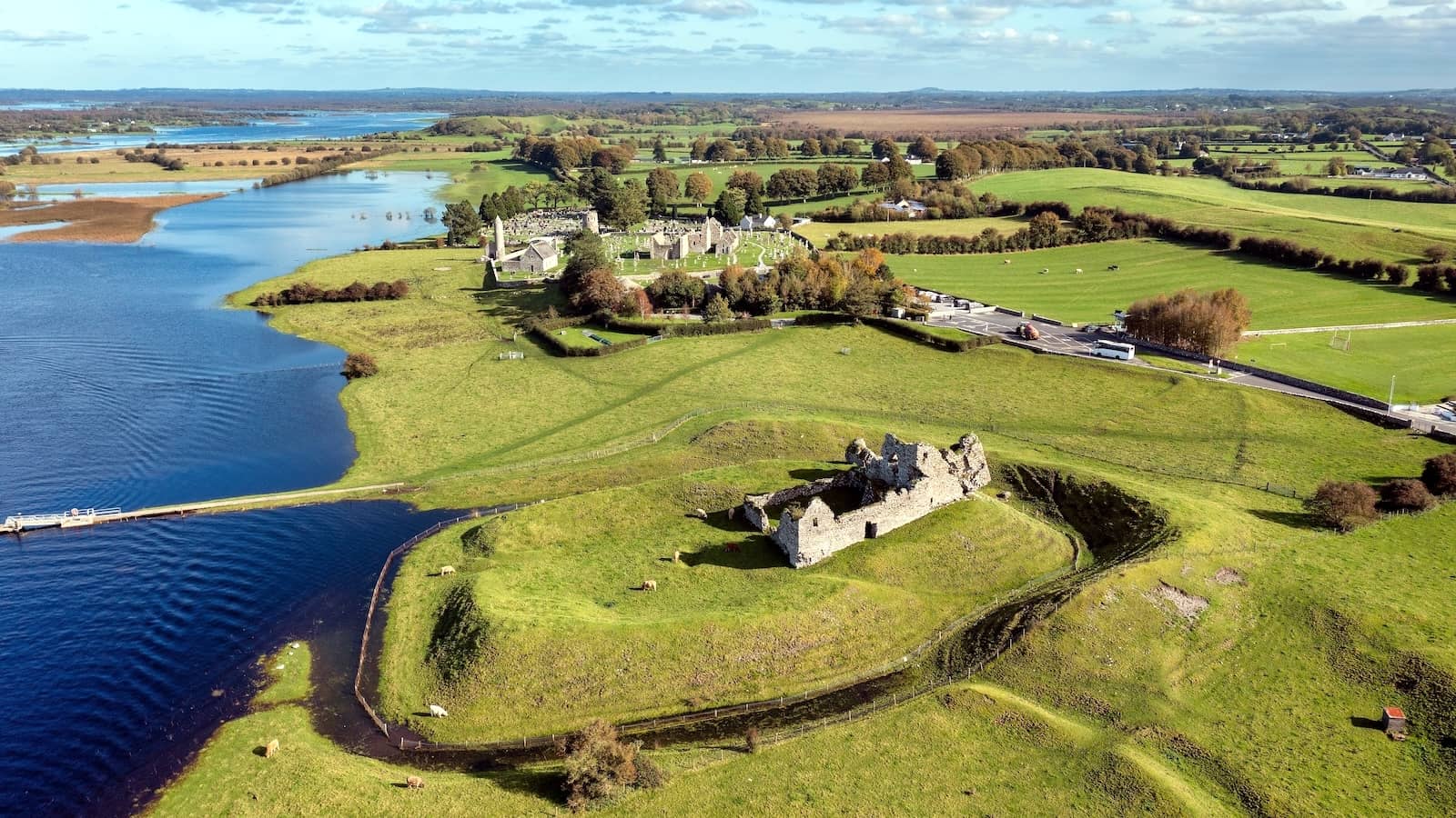 Aerial view of Clonmacnoise monastic site on the River Shannon surrounded by green fields in County Offaly.