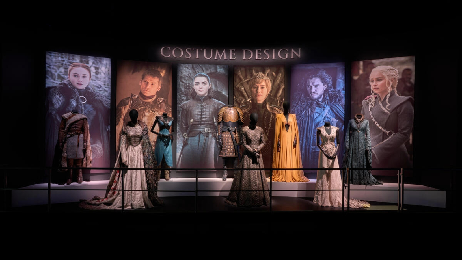 Game of Thrones costume display with gowns and armour in front of character portraits at the Game of Thrones Studio Tour.