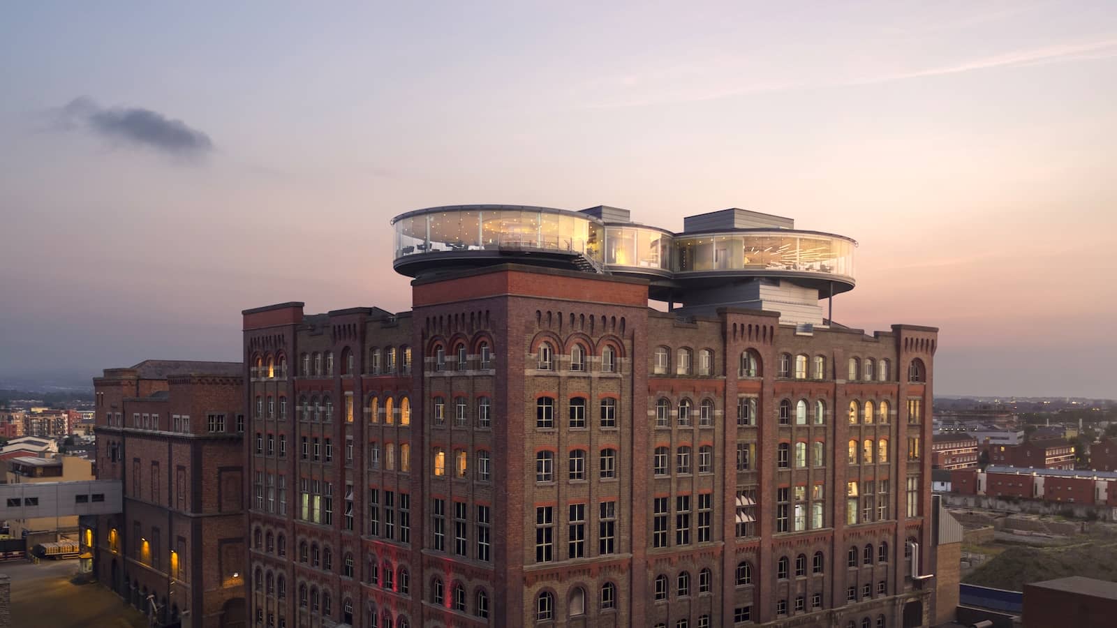 Exterior of the Guinness Storehouse in Dublin at sunset, with the glass-walled Gravity Bar on top.