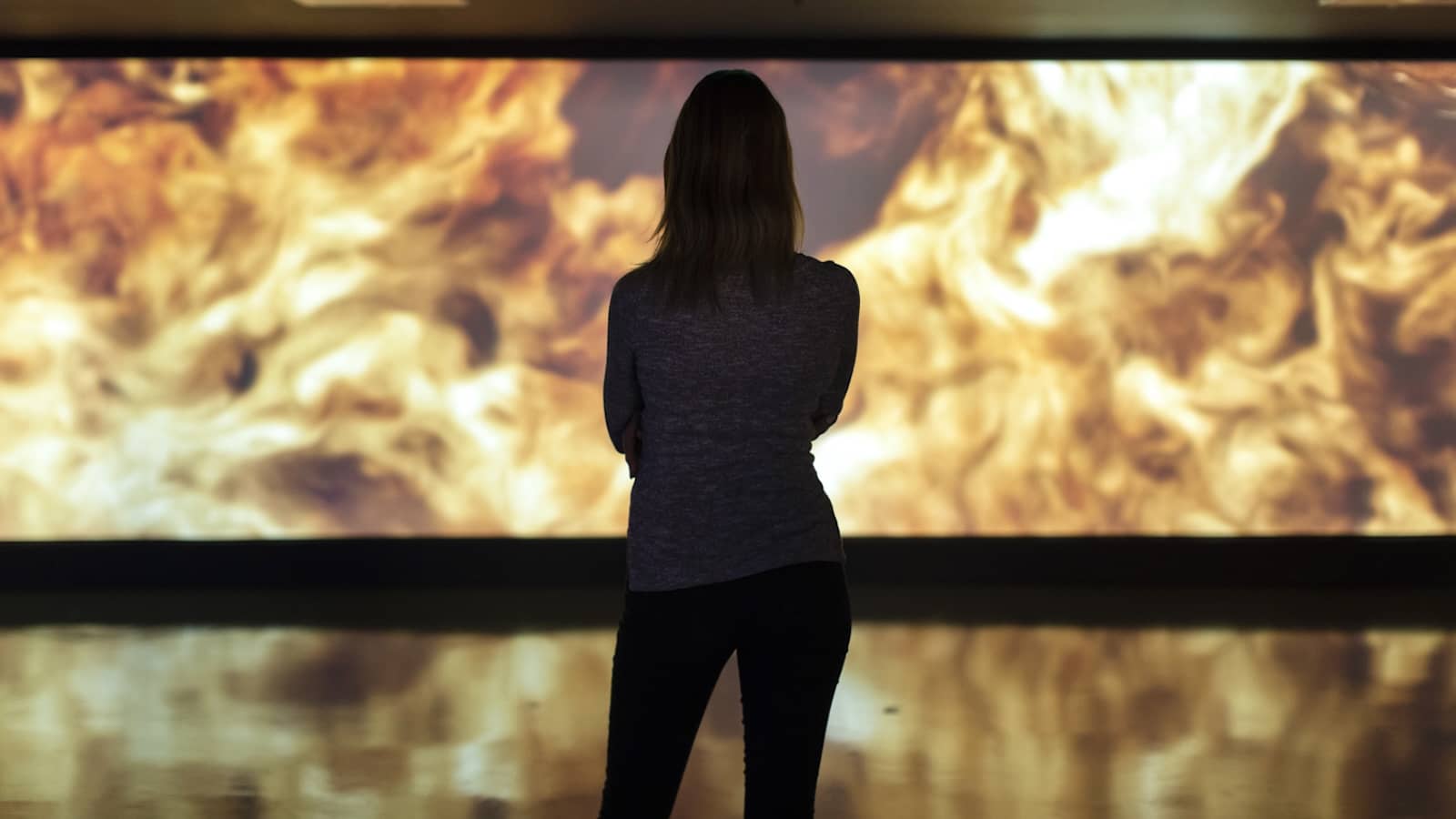 Visitor watching a film at the Guinness Storehouse, Dublin, showing the swirling golden tones of a pint of Guinness being poured.