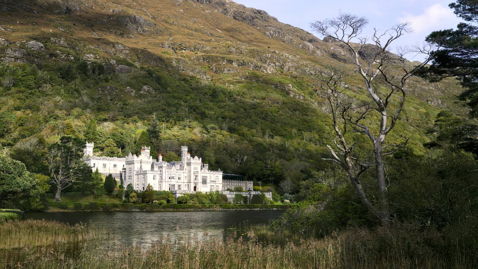 Kylemore Abbey reflected in a lakeshore setting beneath the Connemara mountains in County Galway.