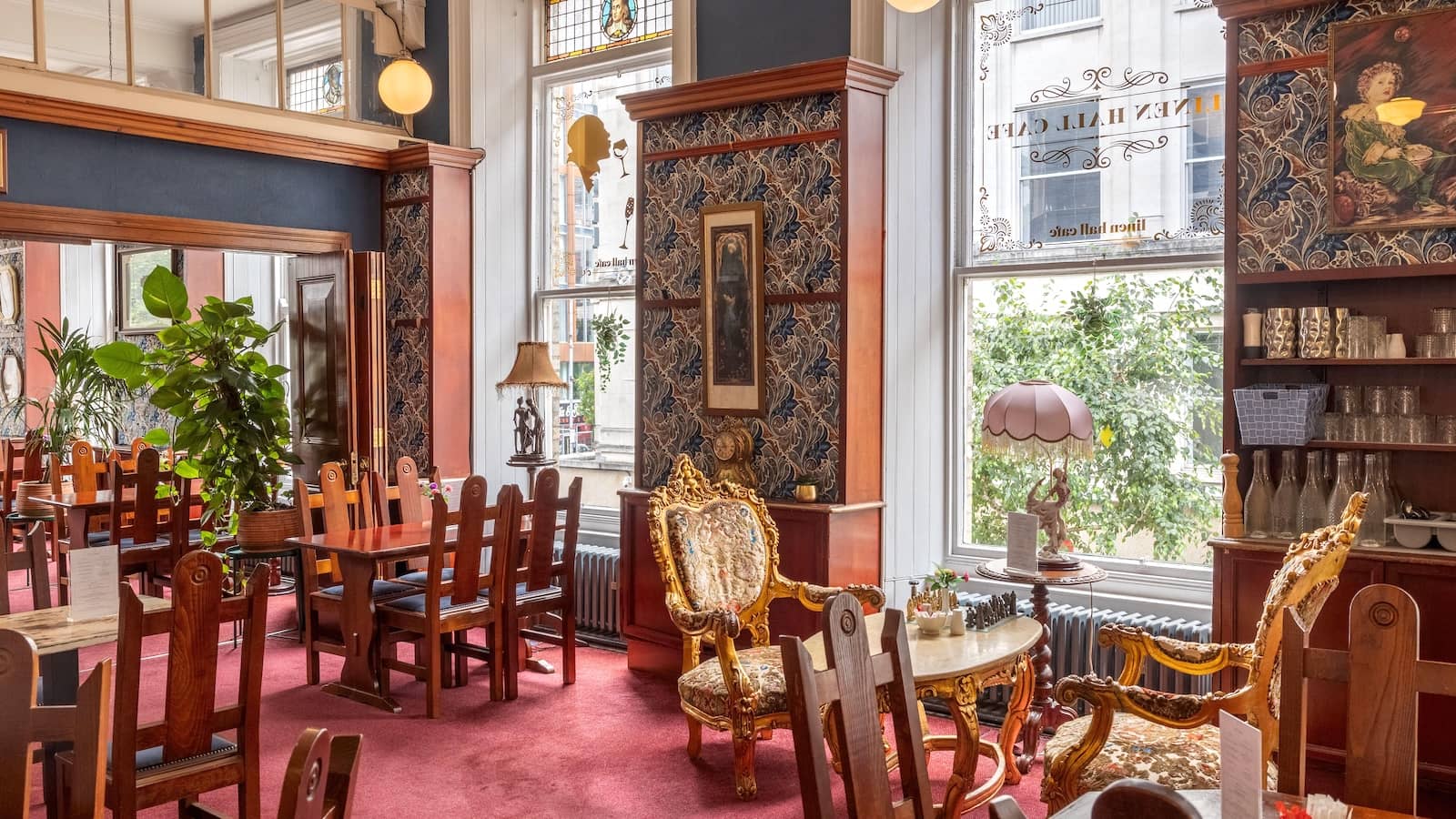 Victorian-style café interior at the Linen Hall Library, Belfast, with ornate chairs and large windows.