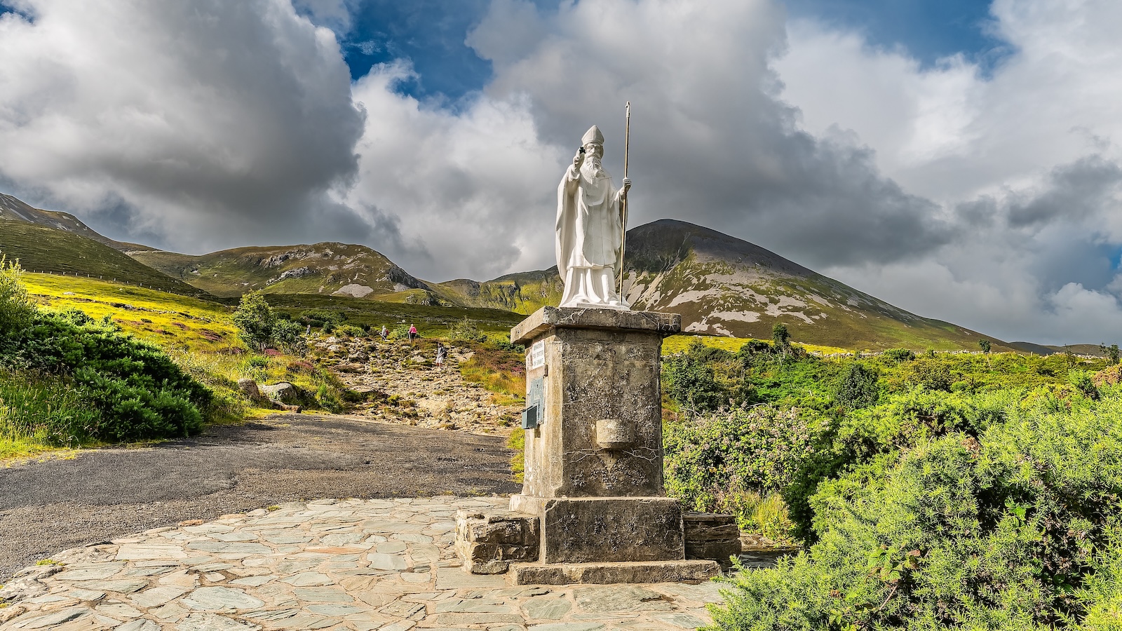 Statue of Saint Patrick at the base of Croagh Patrick with rugged mountains behind.