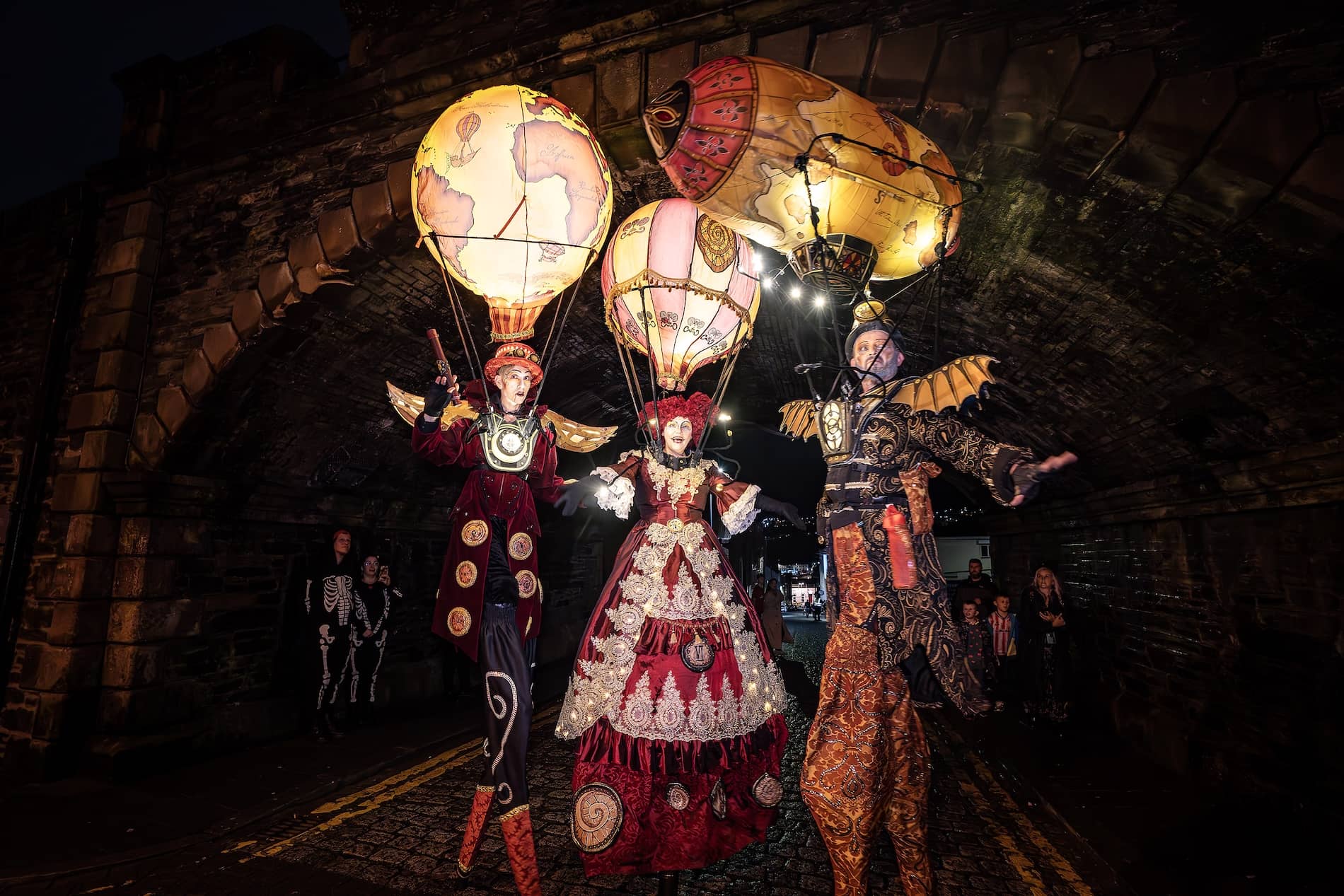 Costumed stilt performers with illuminated hot-air balloons parade through Derry~Londonderry for Halloween.