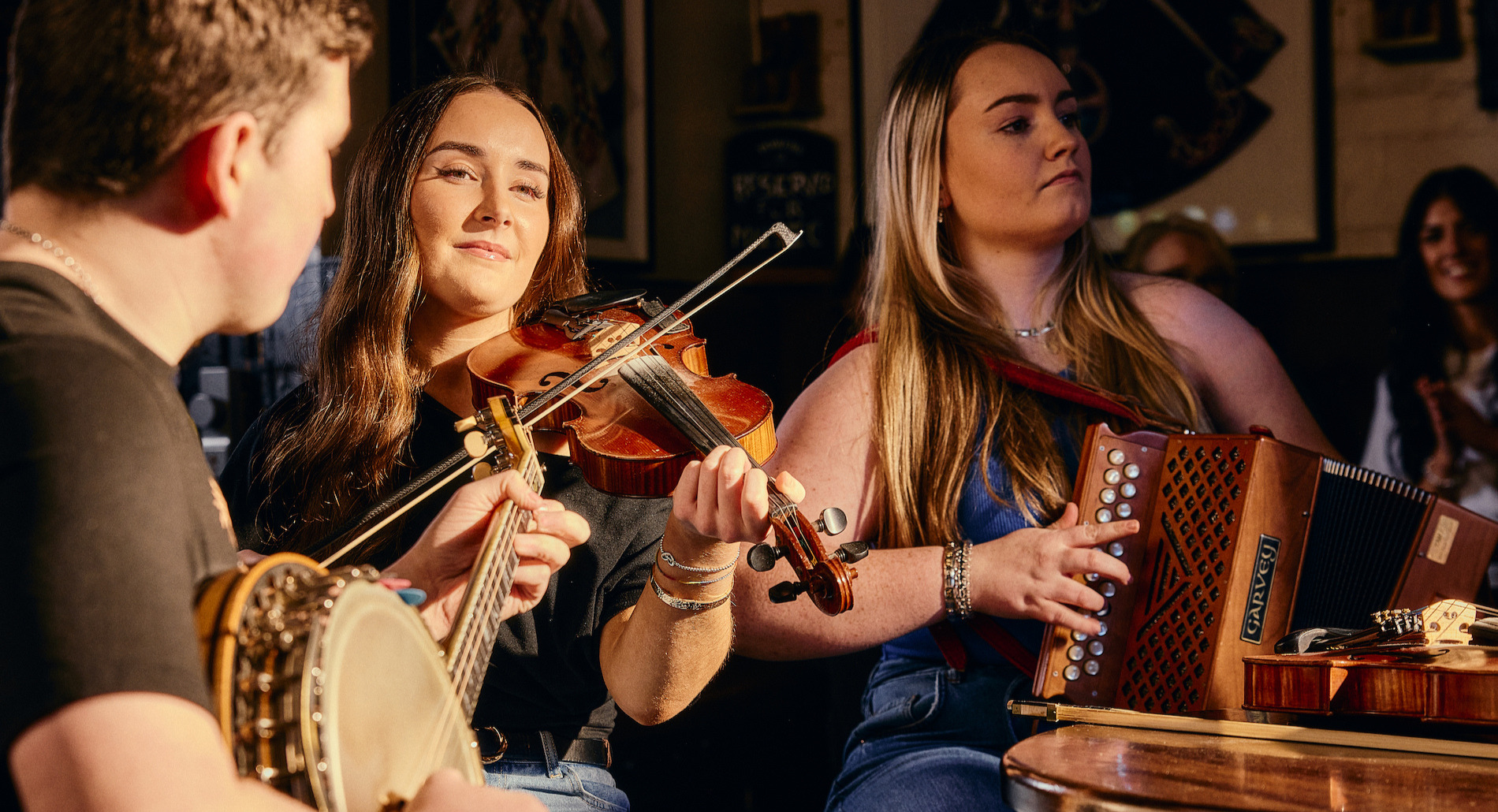 Traditional Irish music session with fiddle, banjo and accordion players performing in a cosy Belfast pub.