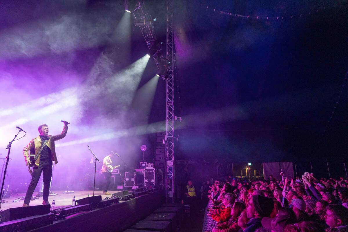 Live band performs on a purple-lit stage to a cheering crowd at the Púca Festival in County Meath.