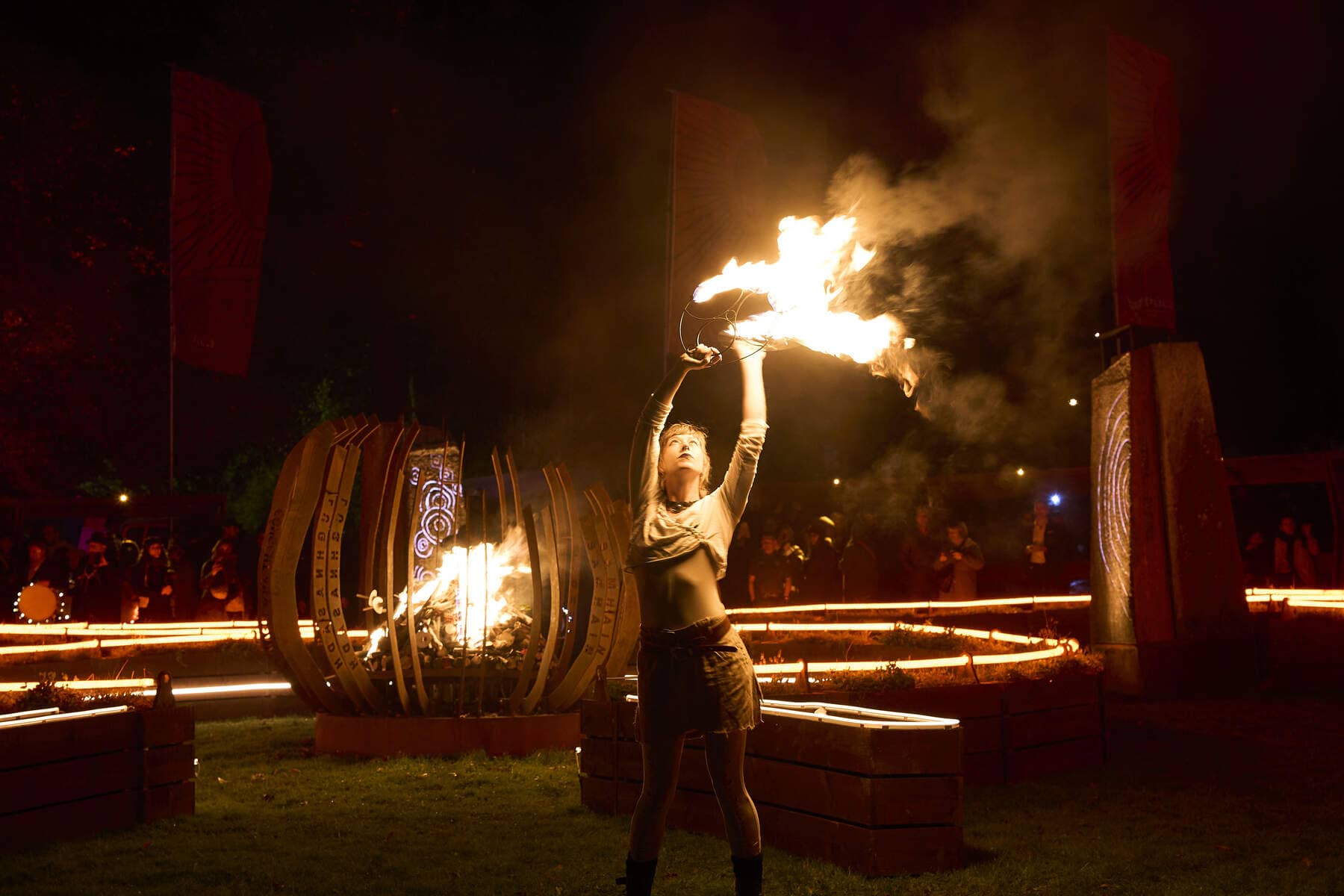 Performer raises flaming props in a dramatic fire display at the Púca Festival in County Meath.