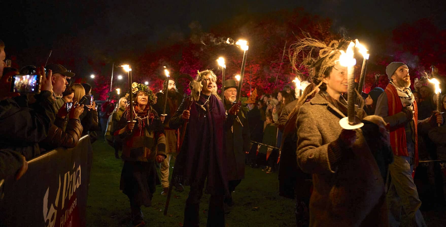 Crowds watch performers carrying flaming torches during the Púca Festival night parade in Ireland.