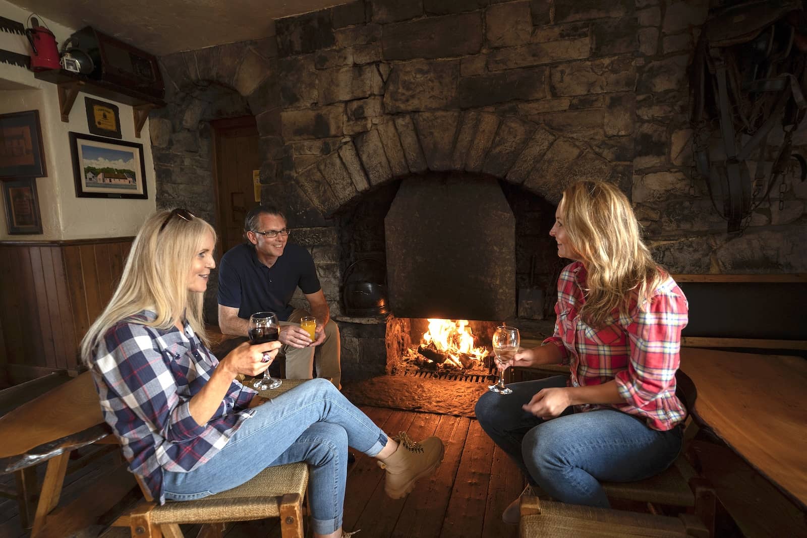Friends relaxing by a stone fireplace in Cassidy's Pub and Restaurant in the Burren, County Clare, enjoying drinks and warm, rustic surroundings.