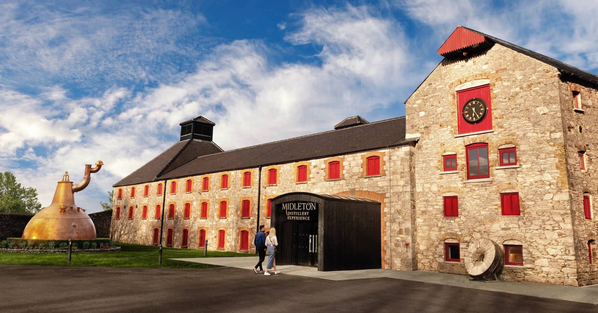 Exterior view of Midleton Distillery Experience, County Cork, with stone buildings and red-trimmed windows.