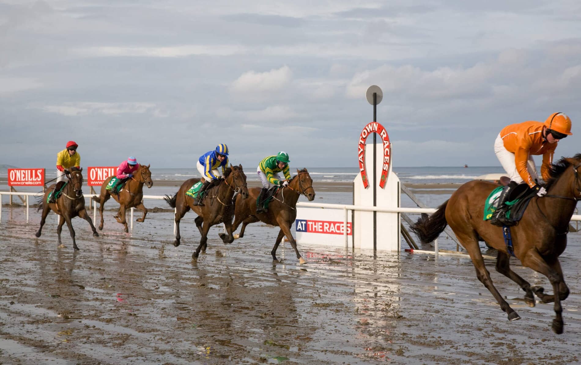 Jockeys on galloping horses race across the wet sands at Laytown Beach, County Meath.
