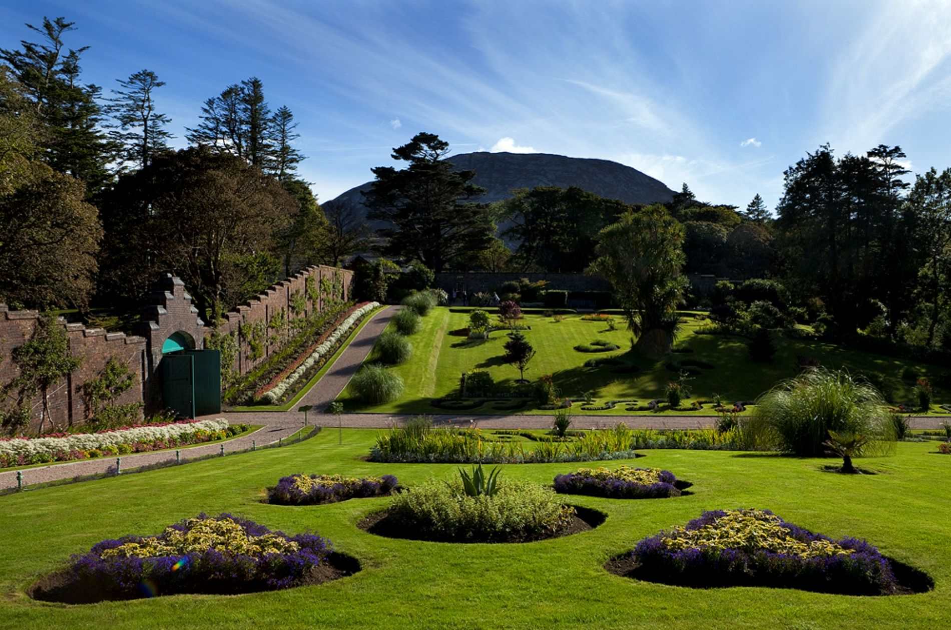 Historic walled garden with manicured lawns and mountain backdrop in Ireland.