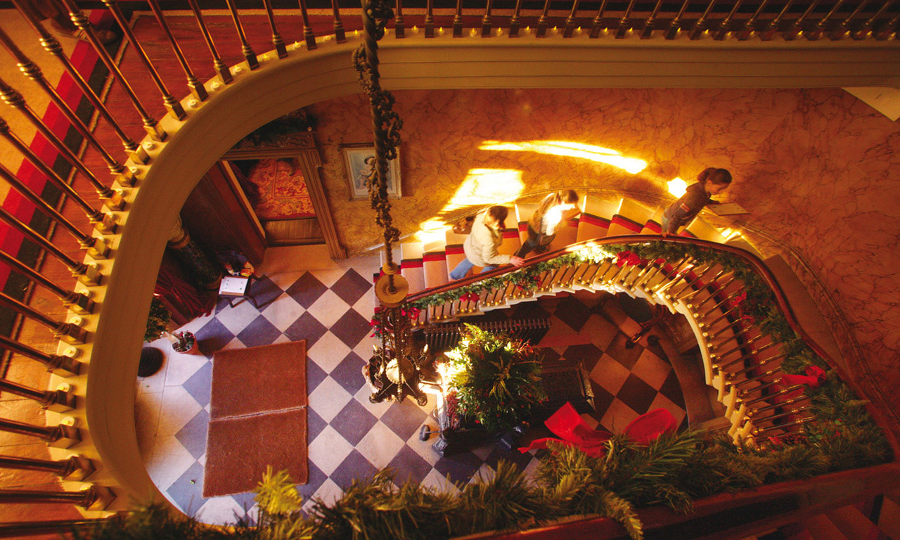 Family walking up a grand staircase decorated with Christmas garlands in Ireland.