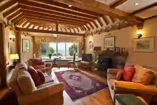 Cosy living room with timber beams, stone fireplace and bay window looking out to the sea in County Meath.