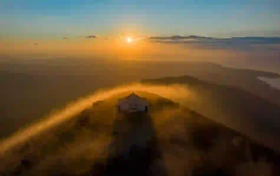 Orange sunset over Croagh Patrick with fog rolling over the mountains and distant sea in County Mayo.
