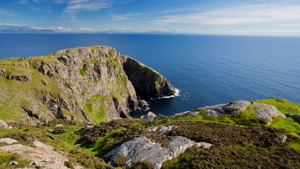 A rocky cliff juts into the Atlantic beneath a clear blue sky in this summer showcase of Ireland’s coastline.