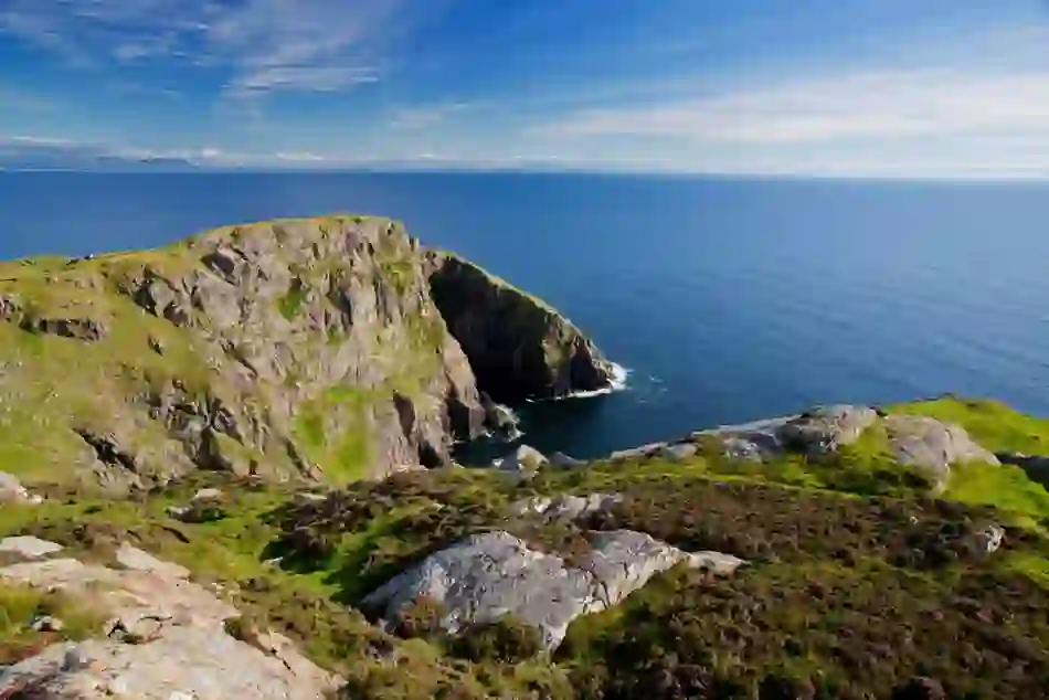 A rocky cliff juts into the Atlantic beneath a clear blue sky in this summer showcase of Ireland’s coastline.
