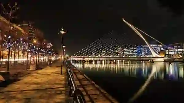 Samuel Beckett Bridge in Dublin lit up at night with festive Christmas lights along the river.