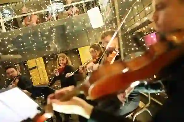 Musicians playing violins and cellos beneath festive Christmas lights at the Guinness Storehouse, Dublin.