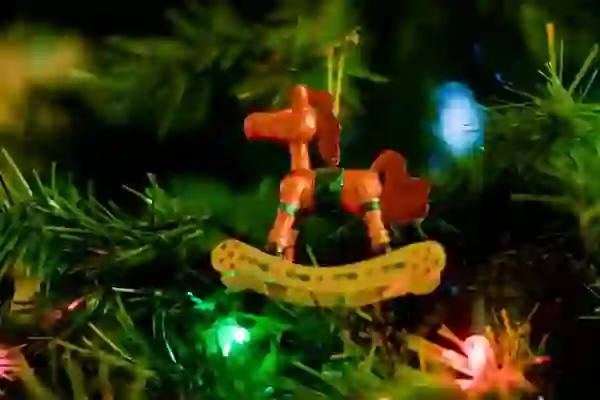 Close-up of a wooden rocking horse Christmas ornament hanging on a decorated tree.