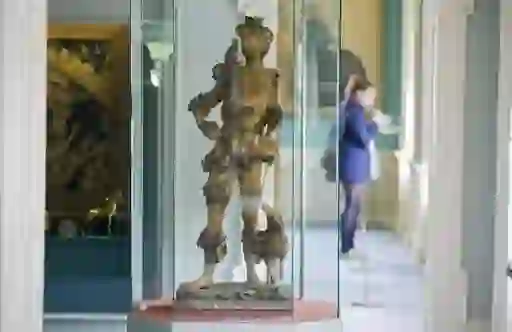 Wooden Renaissance statue of a man in glass case at the Hunt Museum, Limerick, with visitor in background.