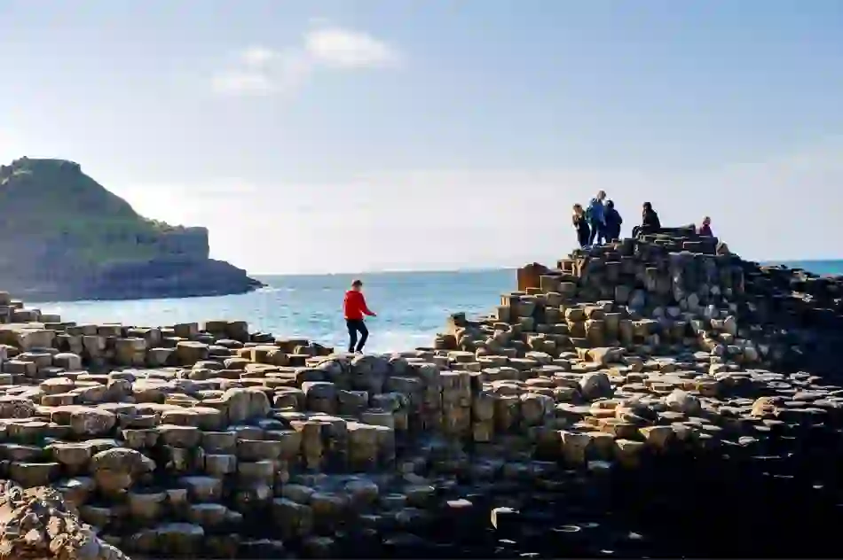 Visitors to the County Antrim coast explore the basalt columns at Giant’s Causeway under a bright sky.