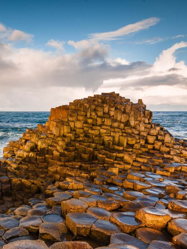 Hexagonal rocks of the Giant’s Causeway meet wild Atlantic waves under a rainbow sky in Northern Ireland.