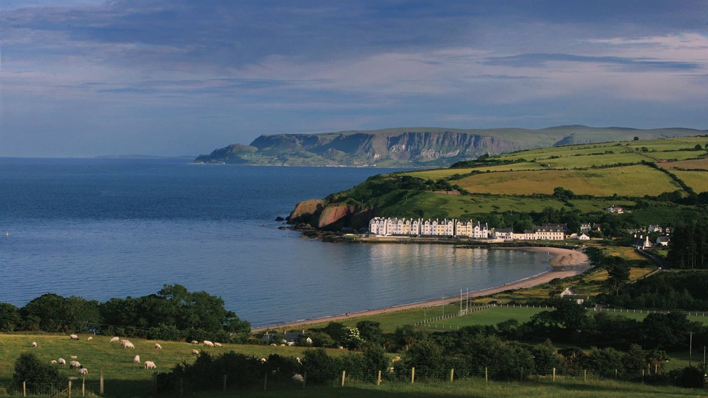 View of Cushendun, a coastal village nestled between cliffs, sea and lush green fields in County Antrim.