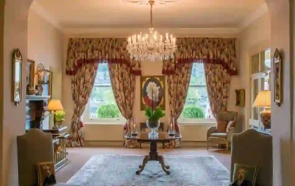 Elegant Perryville with floral curtains, crystal chandelier and antique furniture overlooking a garden view in Kinsale, Cork.
