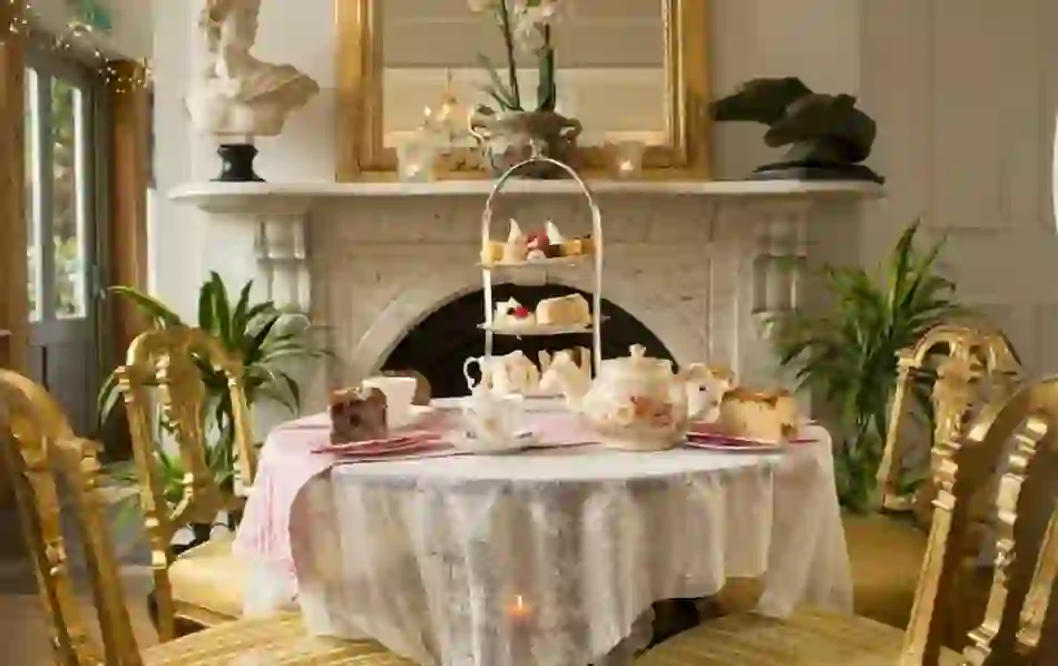 Afternoon tea with cakes and sandwiches on a lace-covered table in Maryville House dining room in Belfast.