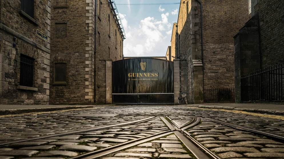 The black Guinness gates at St James’s Gate Brewery in Dublin with cobblestones in the foreground.