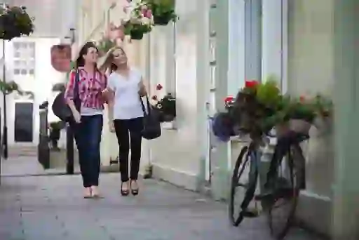 Two women walking along a flower-lined street in Moy, Northern Ireland, on a sunny day.