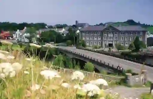 Stone bridge and Georgian-style building in Belleek, County Fermanagh, with hills in the background.