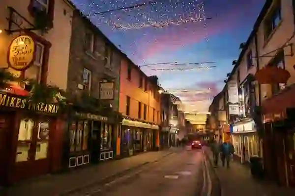 Street in Killarney decorated with Christmas lights and lined with pubs and shops.