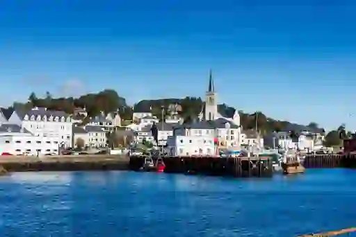 Colourful fishing boats docked beside church and houses in Killybegs harbour. 