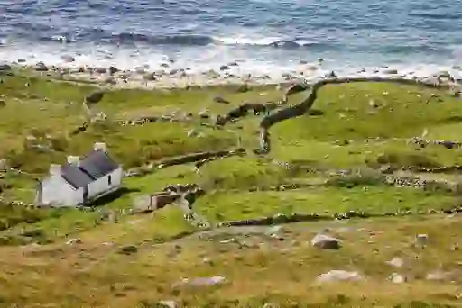 White cottage with stone walls and patchwork fields by the Atlantic at Bloody Foreland, County Donegal.