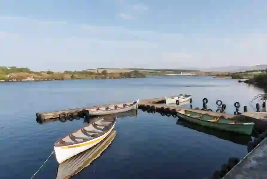 Wooden boats moored at a small harbour in Dungloe, County Donegal, with hills in the distance.