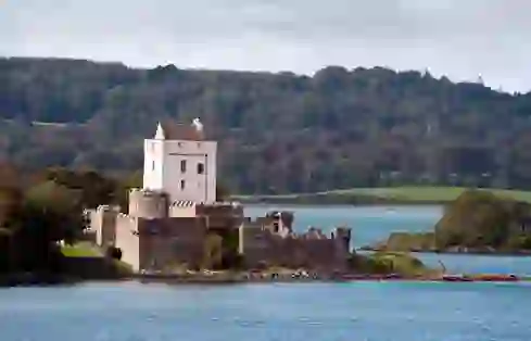 Doe Castle on Sheephaven Bay with white stone walls reflected in the calm waters below.