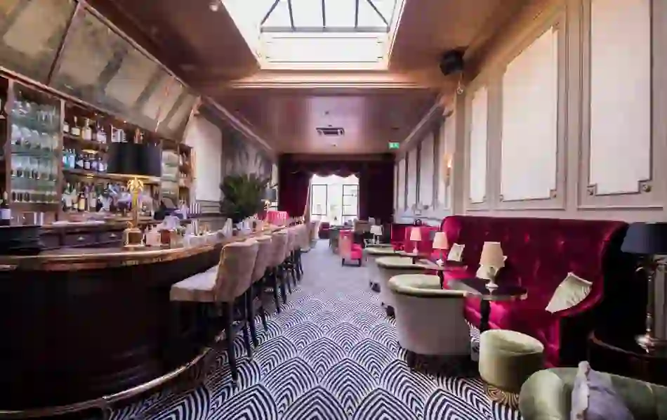 Elegant cocktail bar with velvet seating, patterned carpet and a mirrored backlit counter at the Stella Cinema.