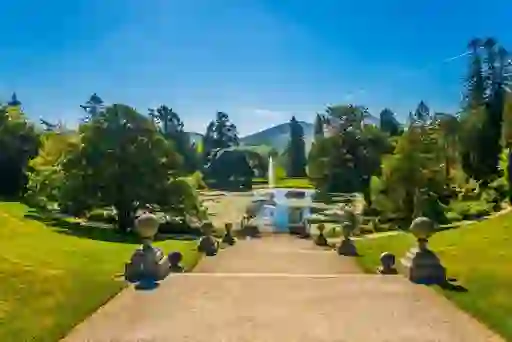 Stone steps lead to a pond with fountain and mountain views at Powerscourt.