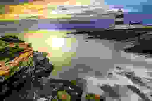 Hook Lighthouse on a rugged Wexford coastline at sunset.